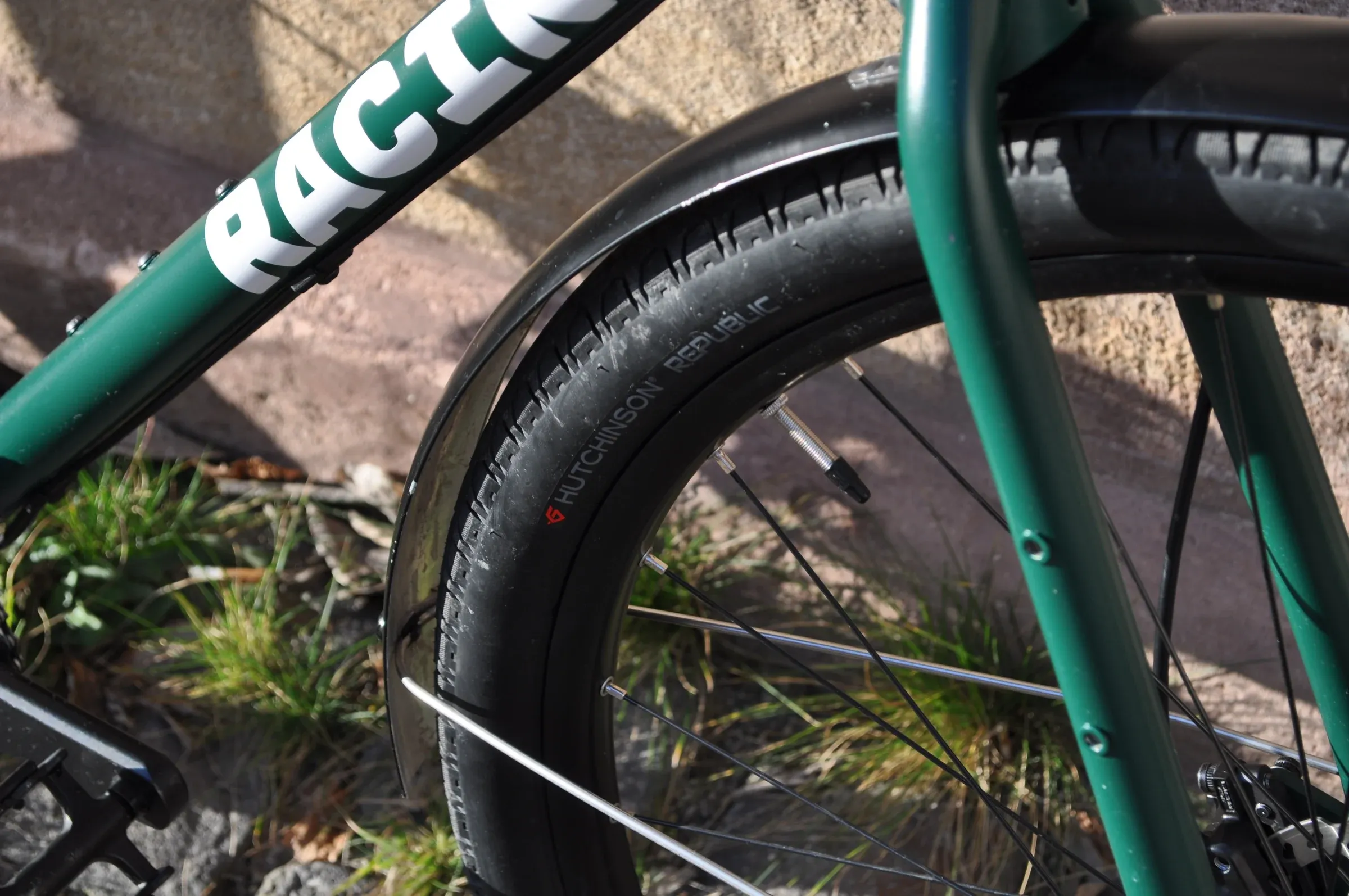 Détail du pneu Hutchinson et du cadre vert mousse du vélo Vélos-Racine, herbe en arrière-plan