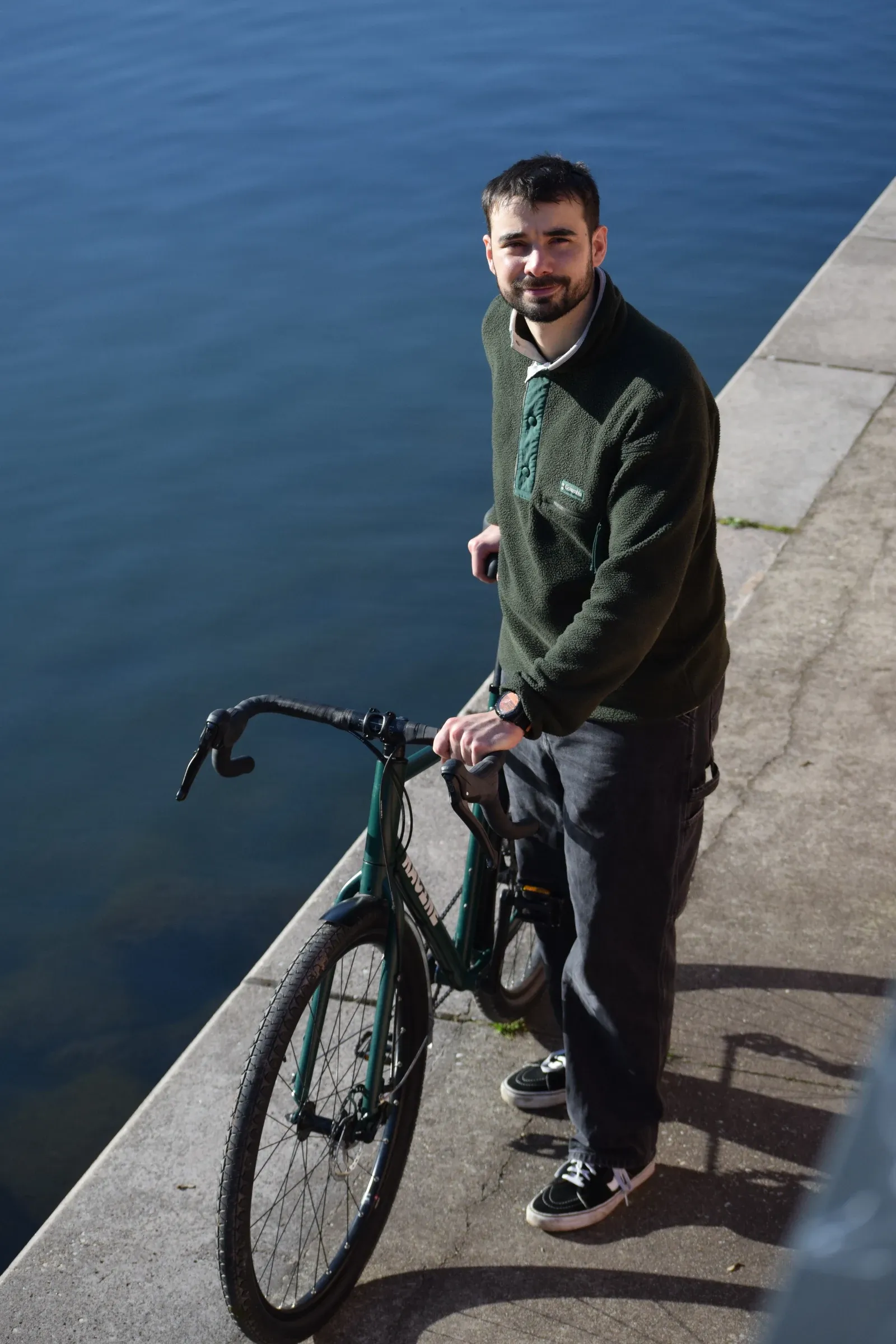 Victor Deweerdt avec le vélo Racine vert mousse sur un quai au bord de l'Ill à Strasbourg